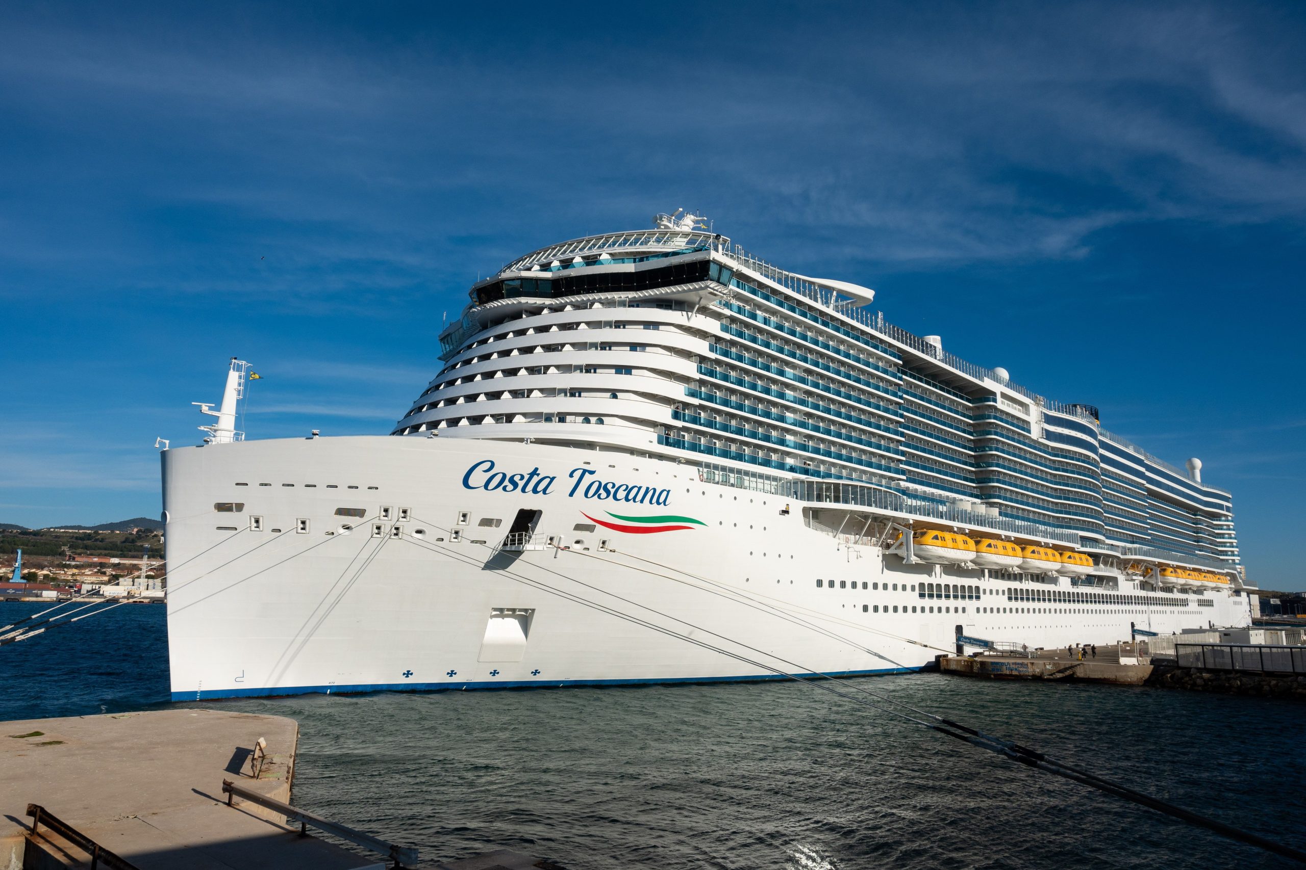 The Costa Toscana cruise ship docked at port under a clear blue sky, ready for passengers.