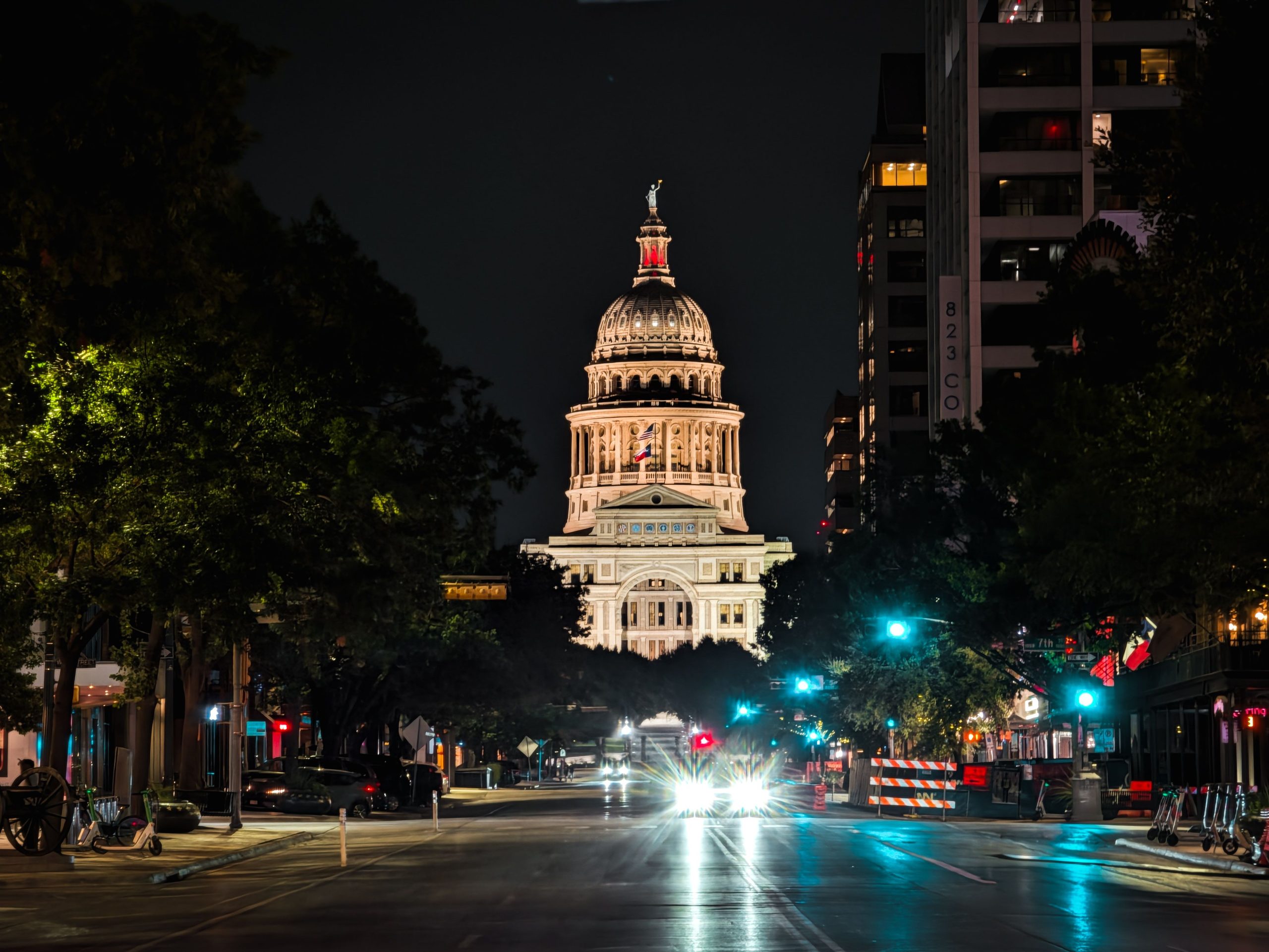 Night view of the illuminated Texas Capitol Building in Austin, captured from downtown street.